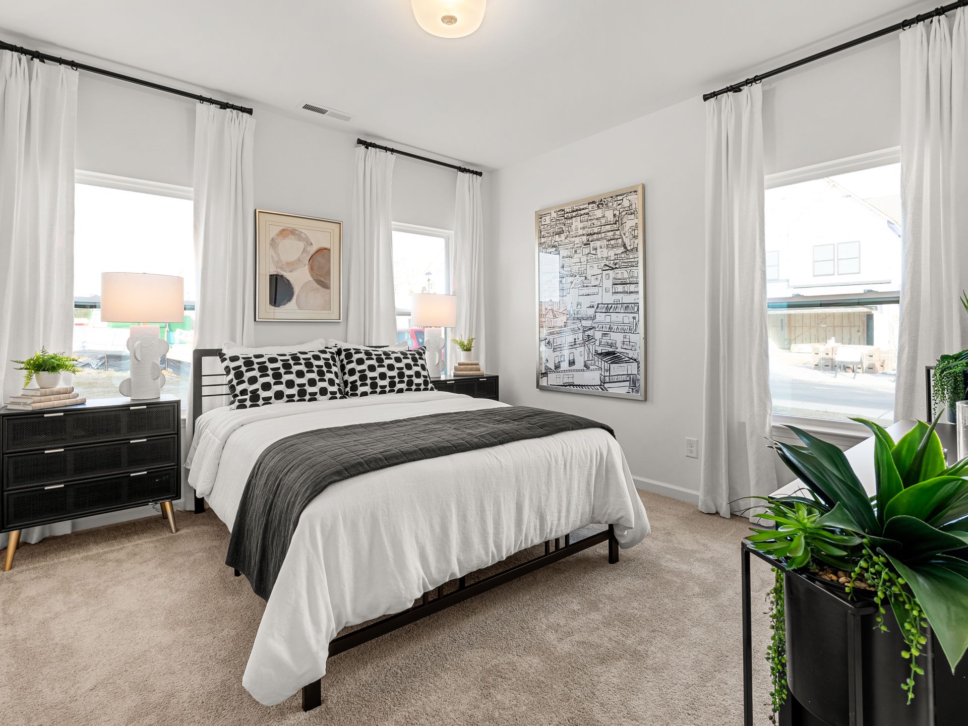 A bedroom with a bed , dresser , nightstand , and two windows.