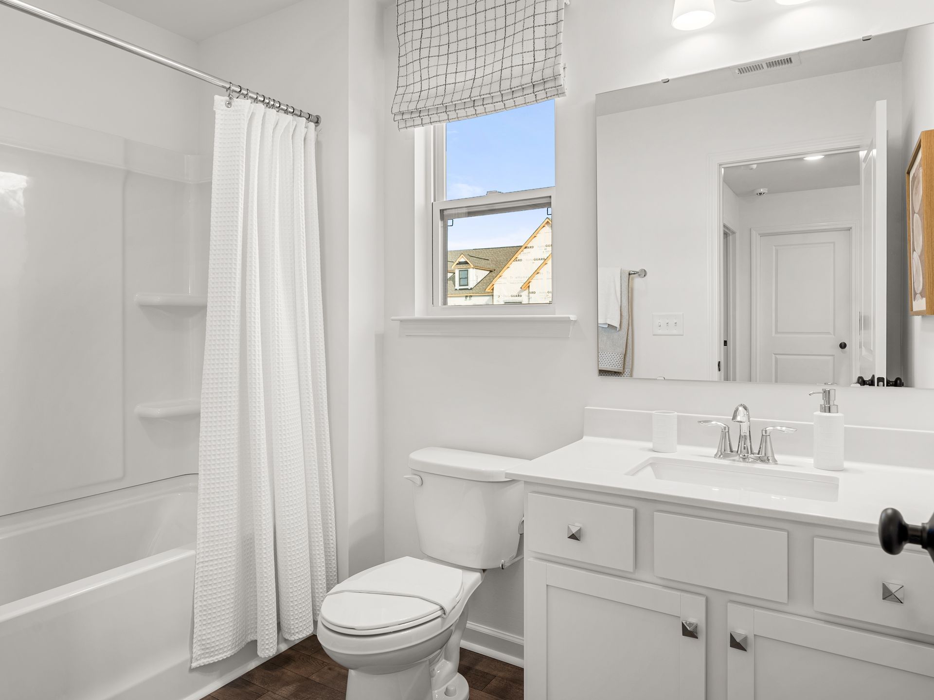 A bathroom with a toilet , sink , shower and mirror.