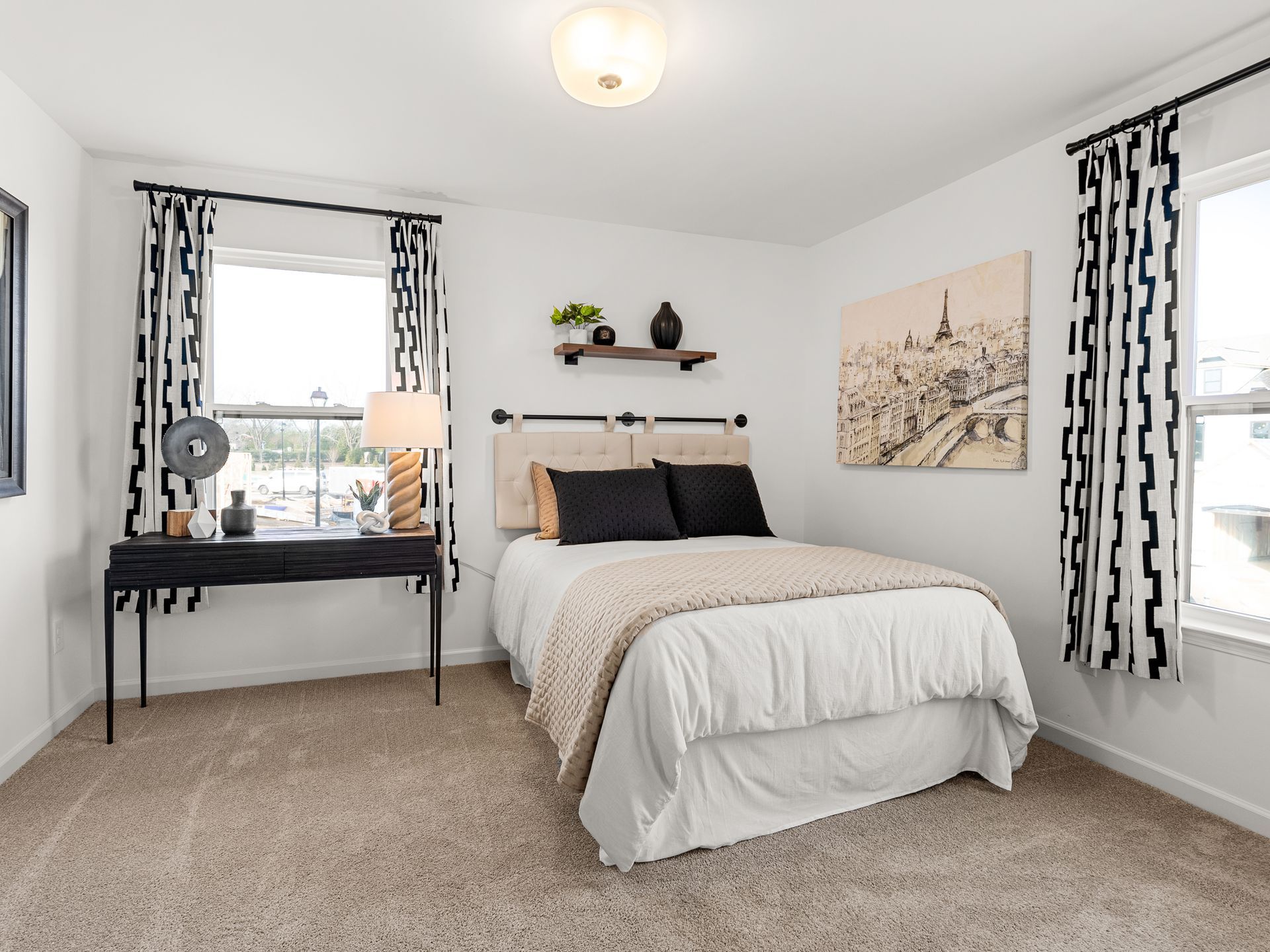 A bedroom with a bed , desk , and two windows.