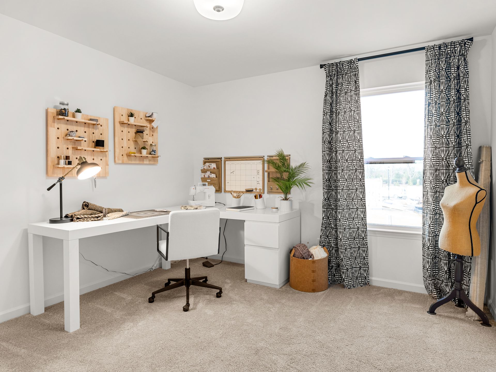 A room with a desk , chair , lamp and window.