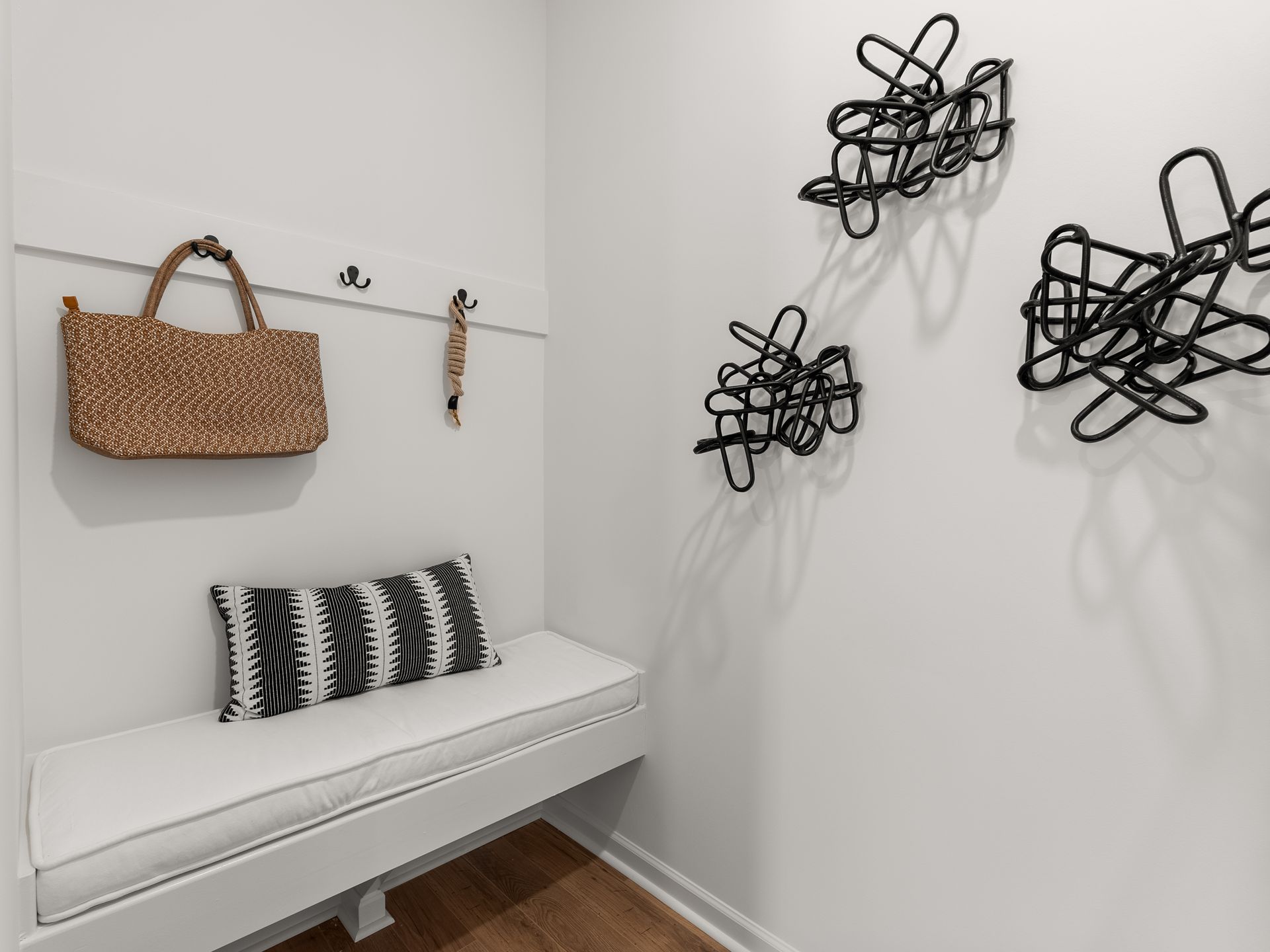 There is a bench in the hallway with a purse hanging on the wall.