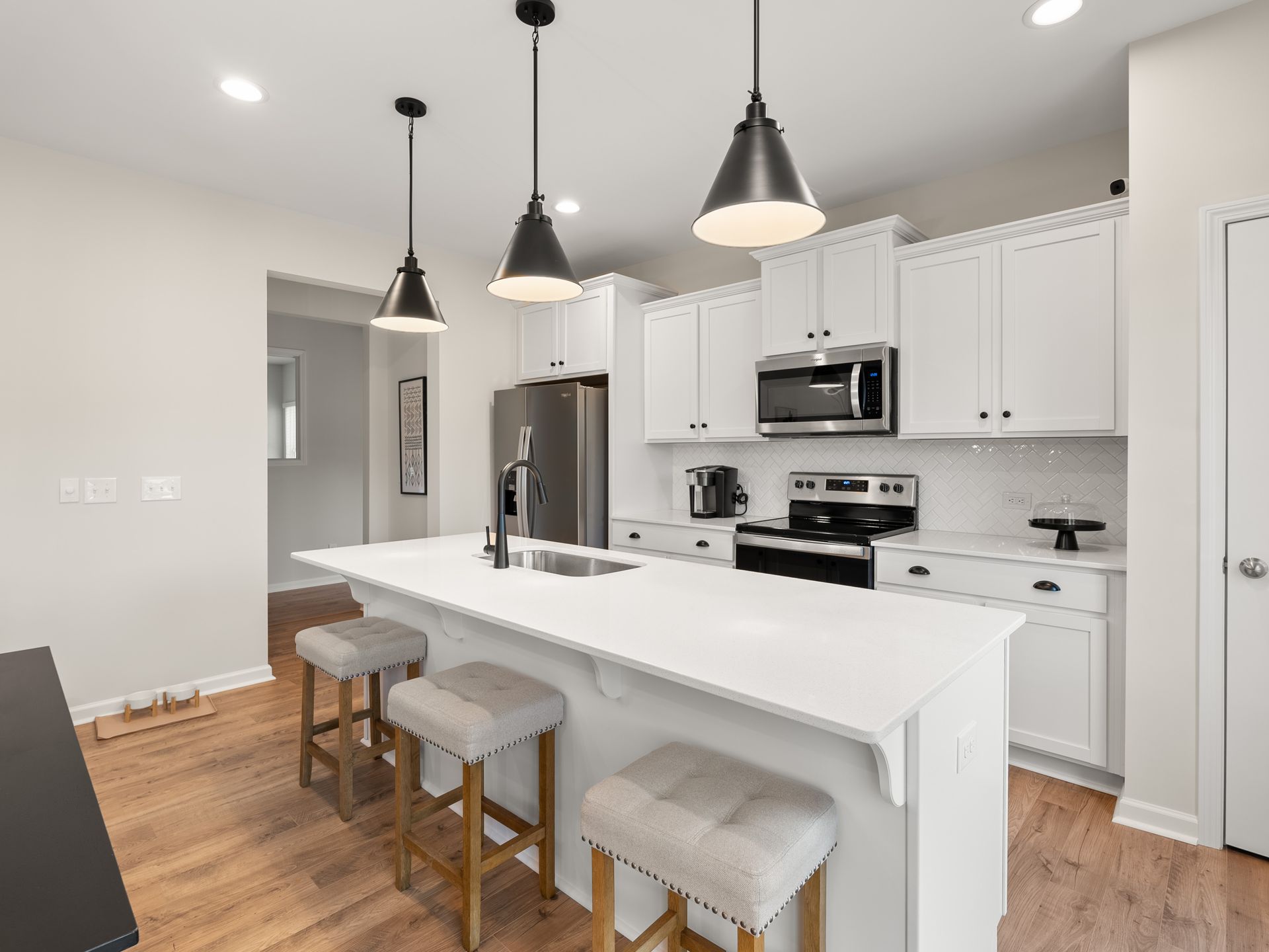 A kitchen with white cabinets , stainless steel appliances , and a large island.