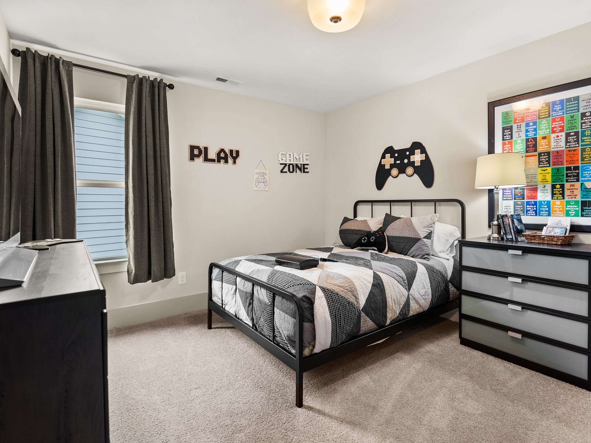 A bedroom with a bed , dresser , and a video game controller on the wall.