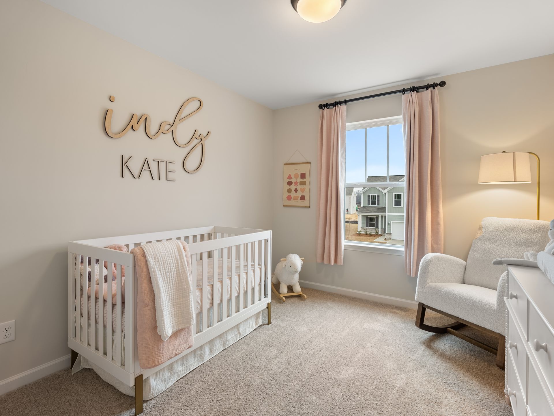 A nursery with a crib , rocking chair , dresser and window.