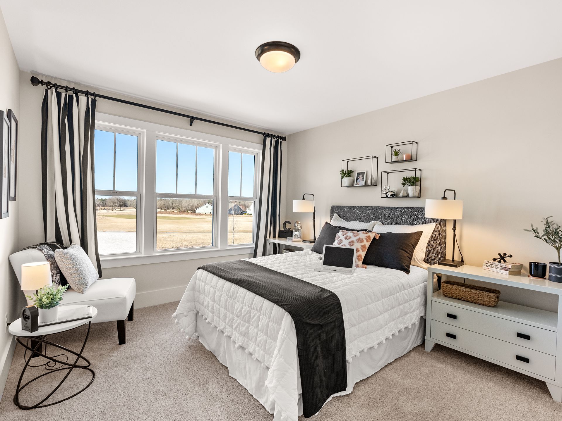A bedroom with a bed , chair , nightstand and windows.