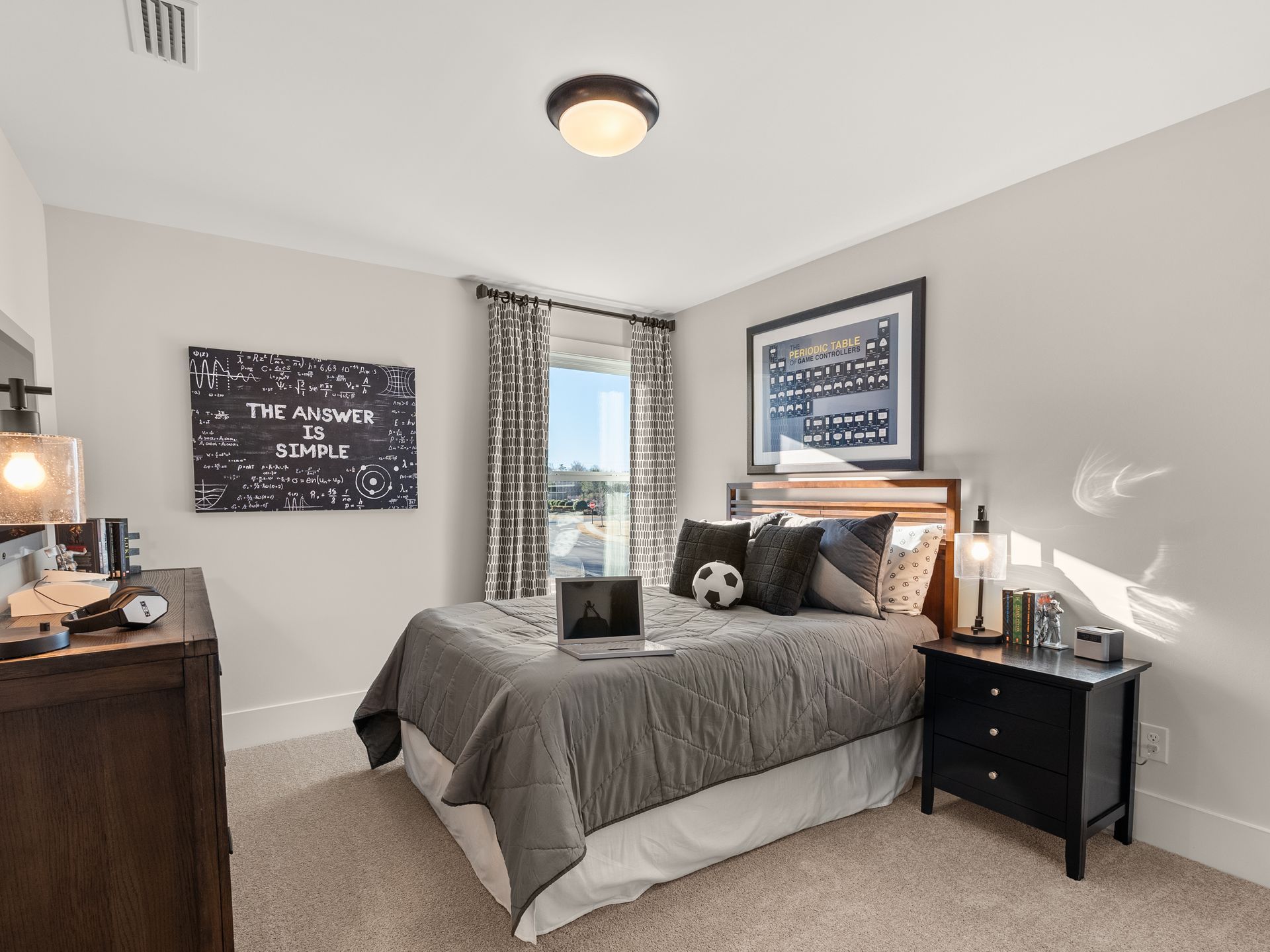 A bedroom with a bed , nightstand , dresser and window.