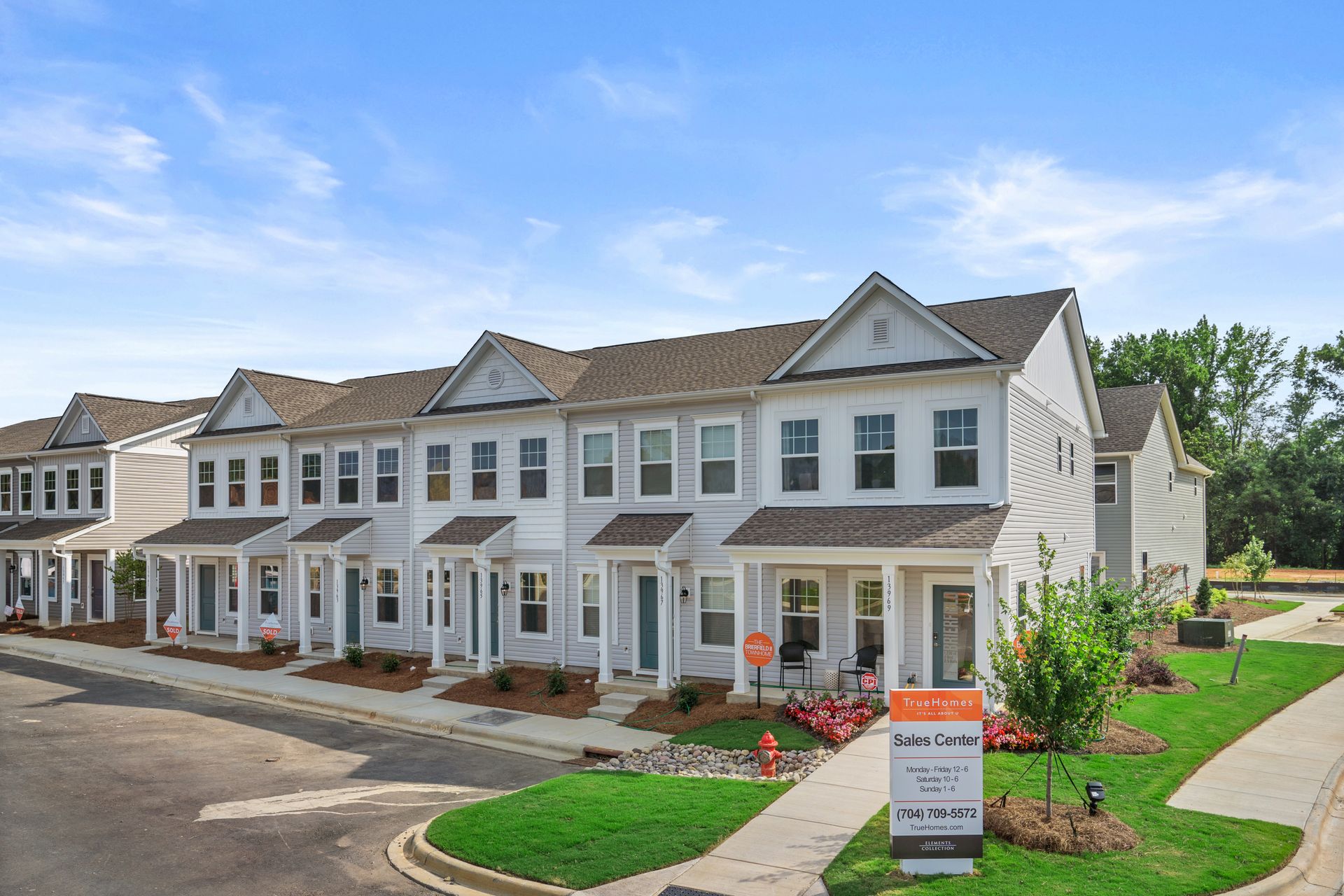 a row of houses with a for sale sign in front of them .