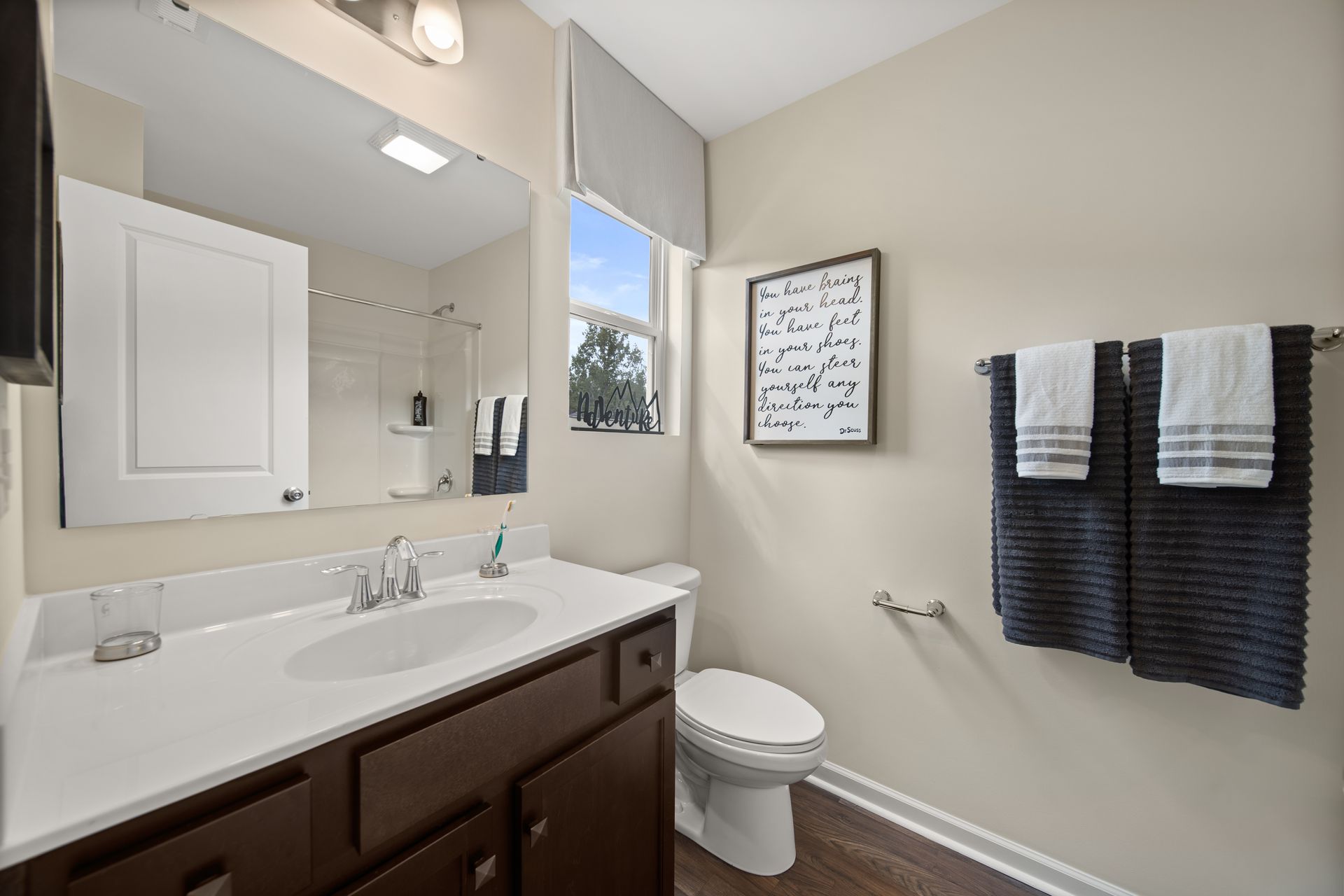 a bathroom with a sink , toilet , mirror and towels .
