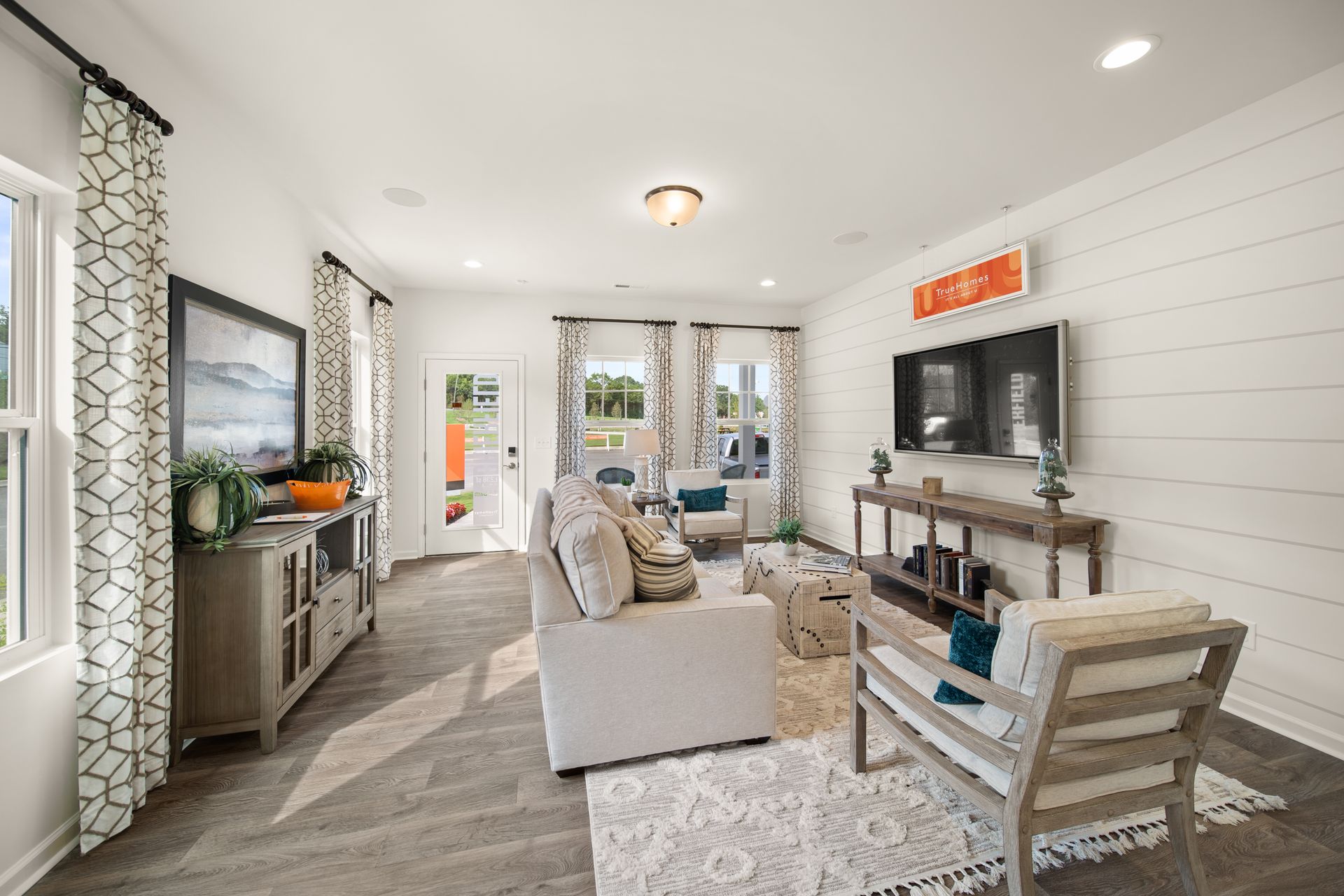 a living room with a couch , chairs , and a flat screen tv .