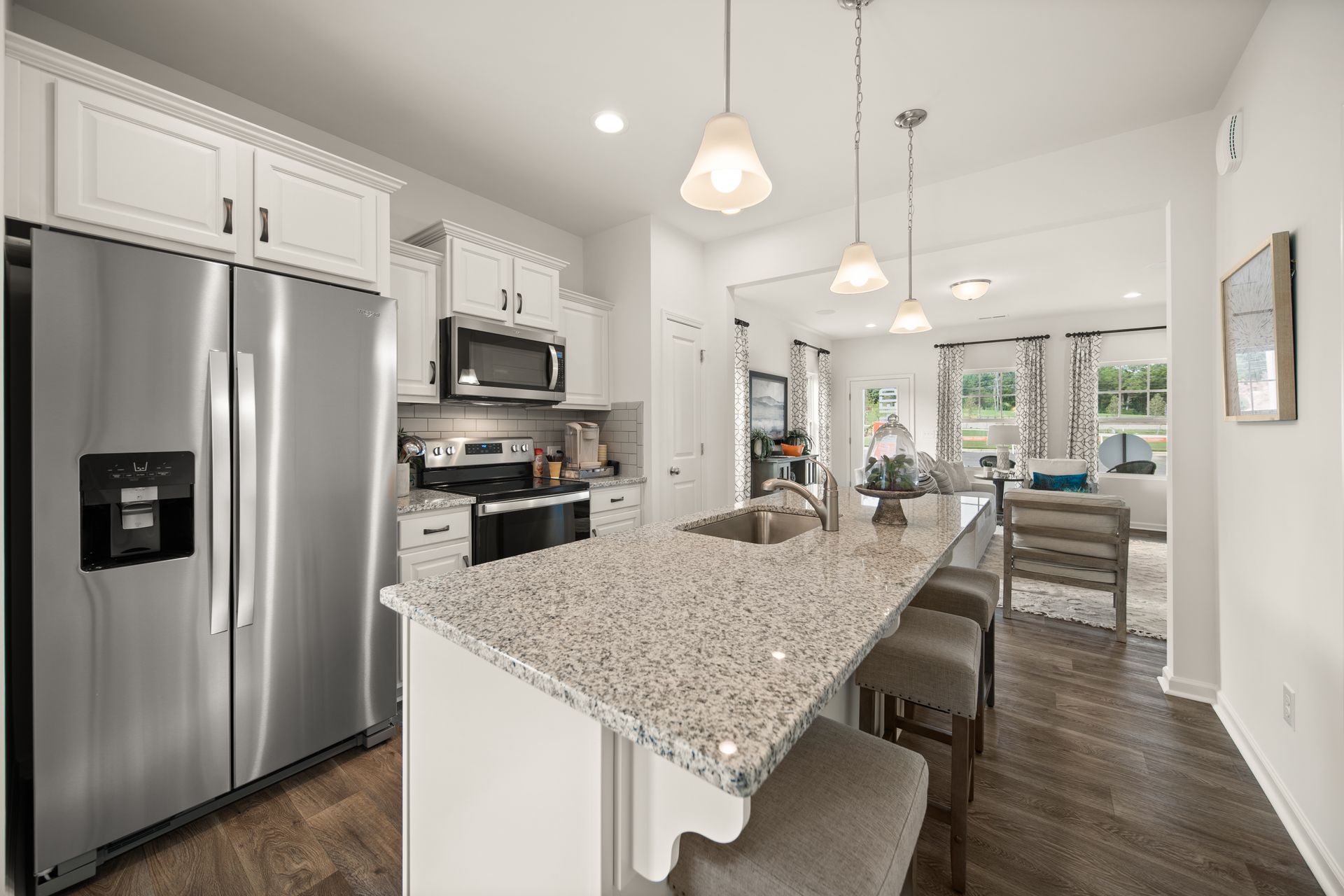 a kitchen in a model home with granite counter tops and stainless steel appliances .