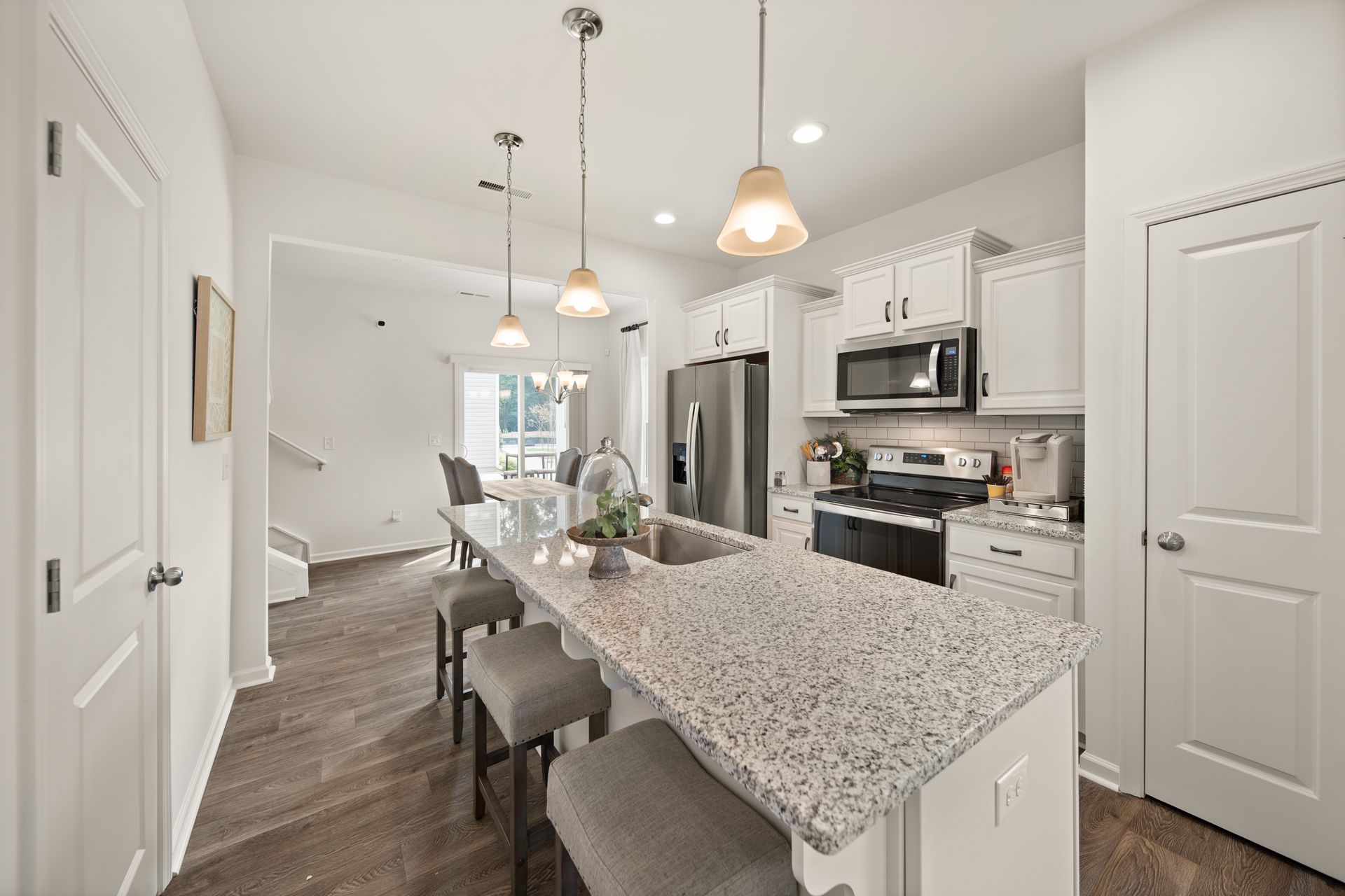 a kitchen with granite counter tops , white cabinets , stainless steel appliances and a large island .