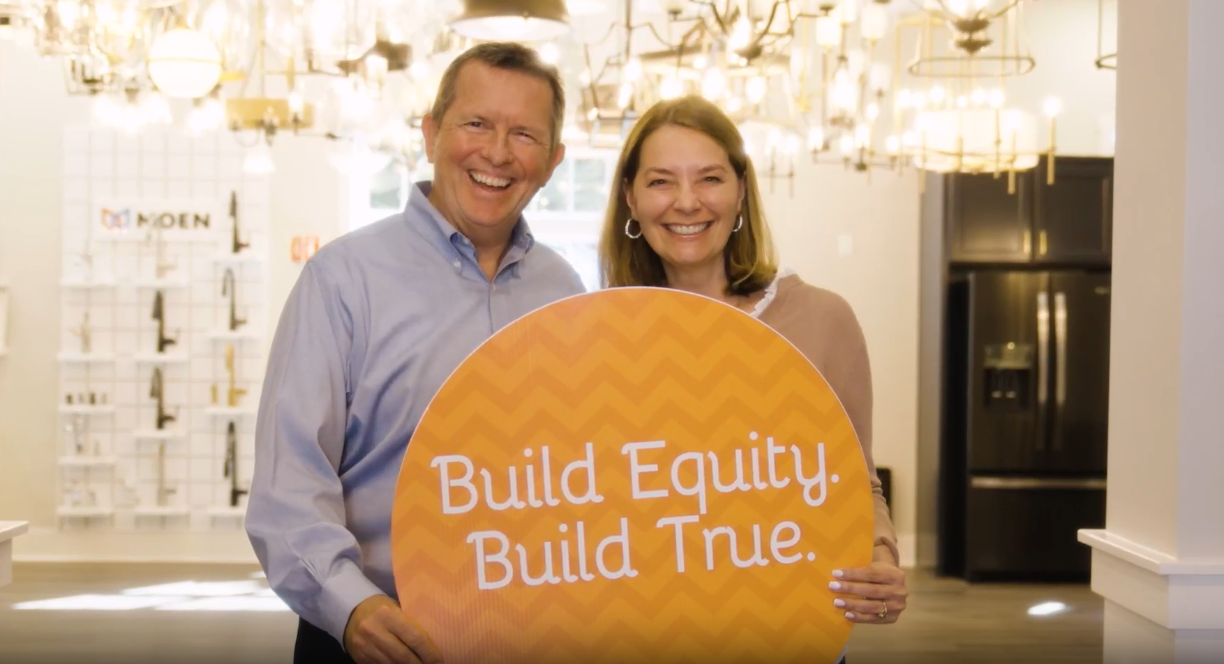 A man and a woman are holding a sign that says `` build equity build true ''.