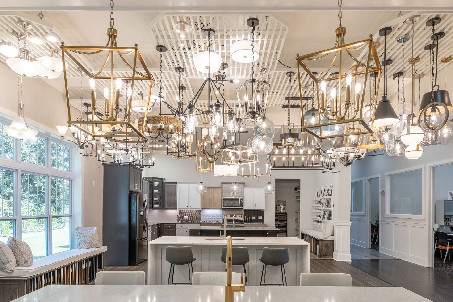 Interior showroom with various hanging light fixtures above a kitchen island, counter, and window seating.