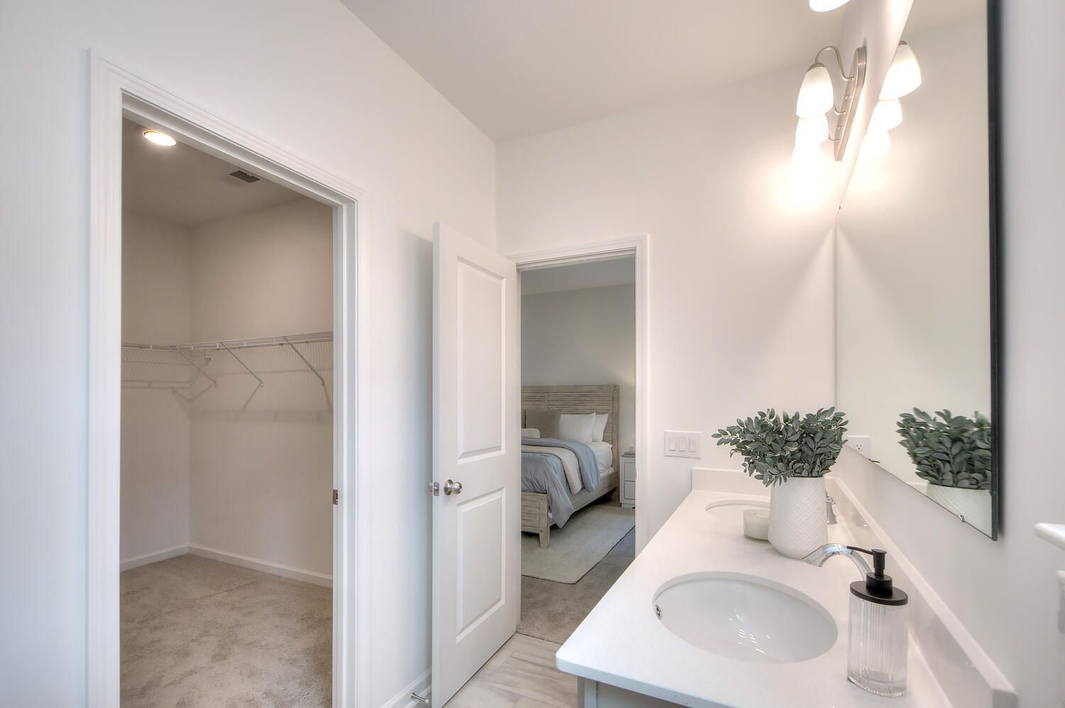 A bathroom with two sinks , a mirror and a walk in closet.
