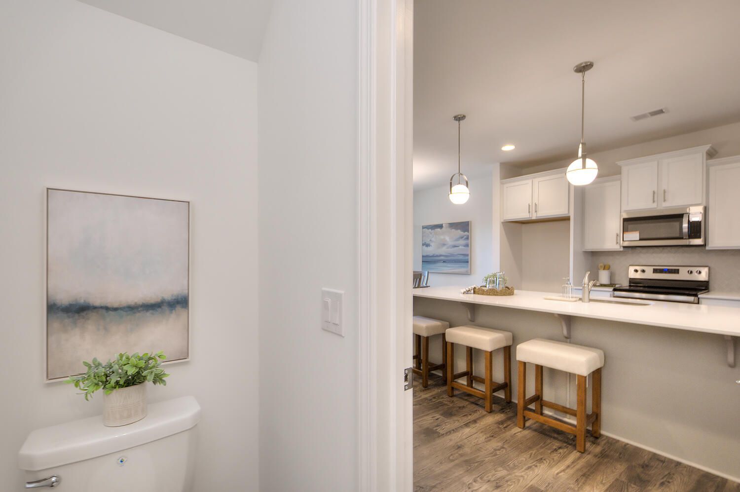 A bathroom with a toilet and stools next to a kitchen.