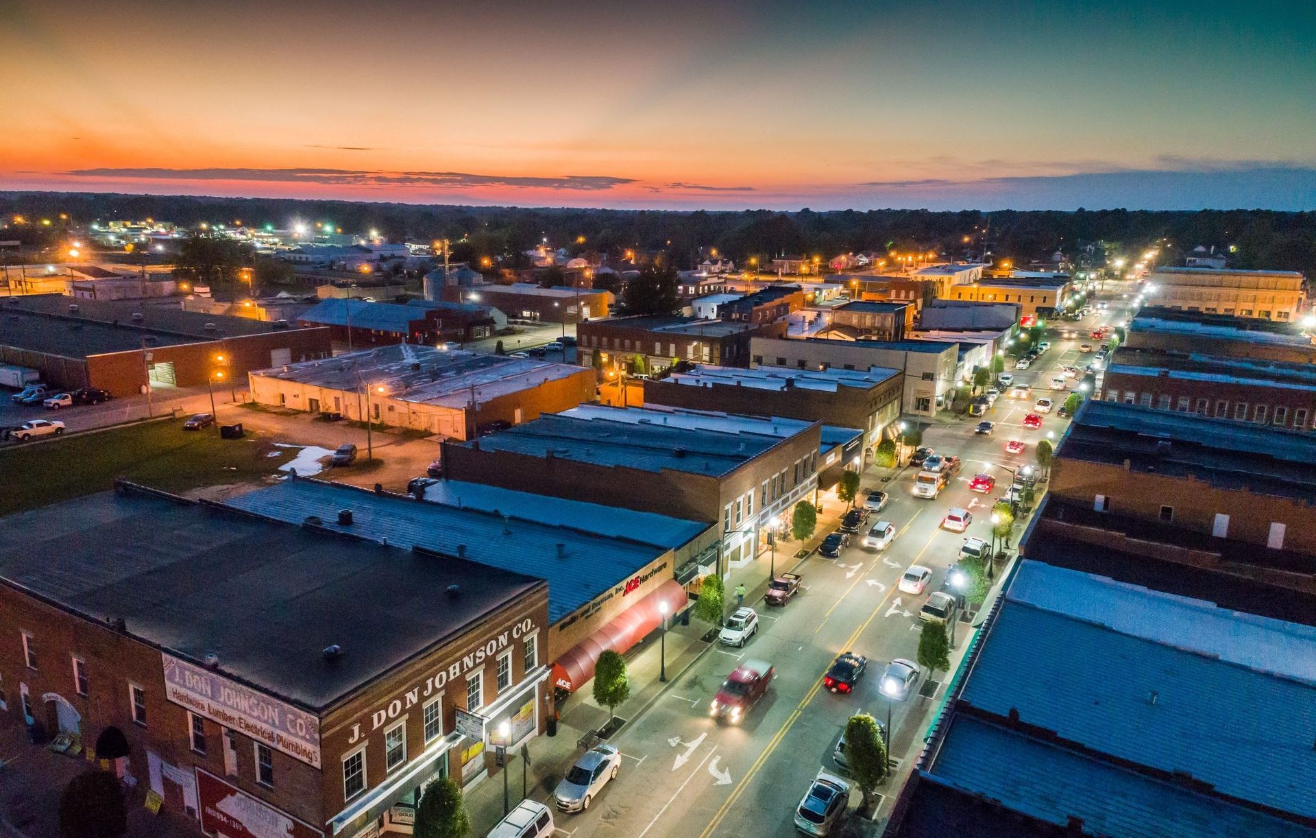 An aerial view of a small town at night with a sunset in the background.