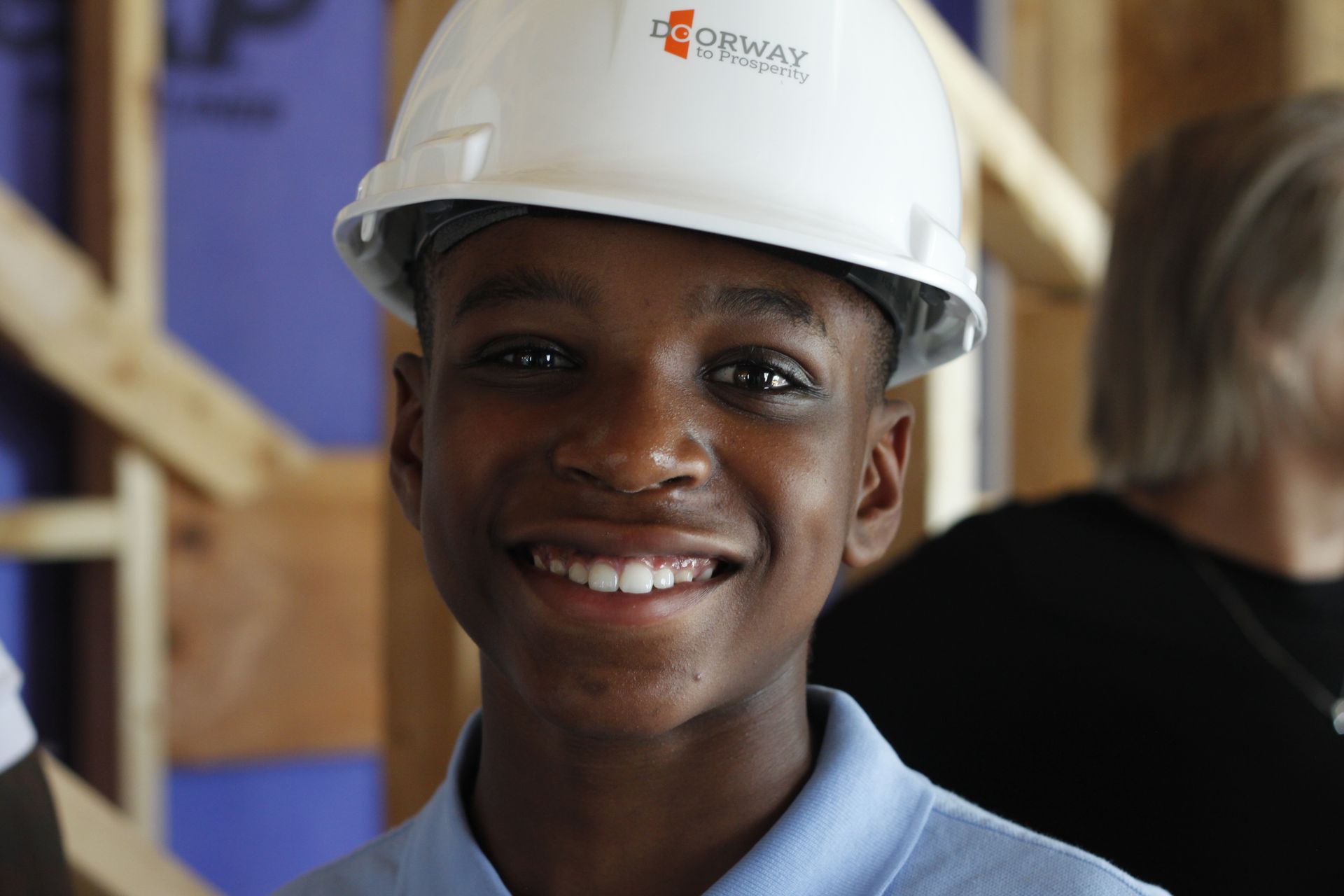 A young boy wearing a hard hat is smiling for the camera.