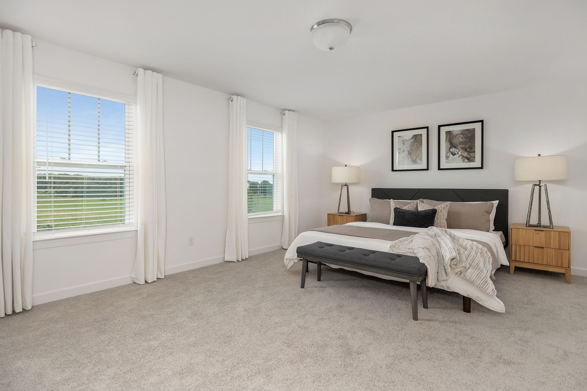 A bedroom with a large bed , two windows and a bench.