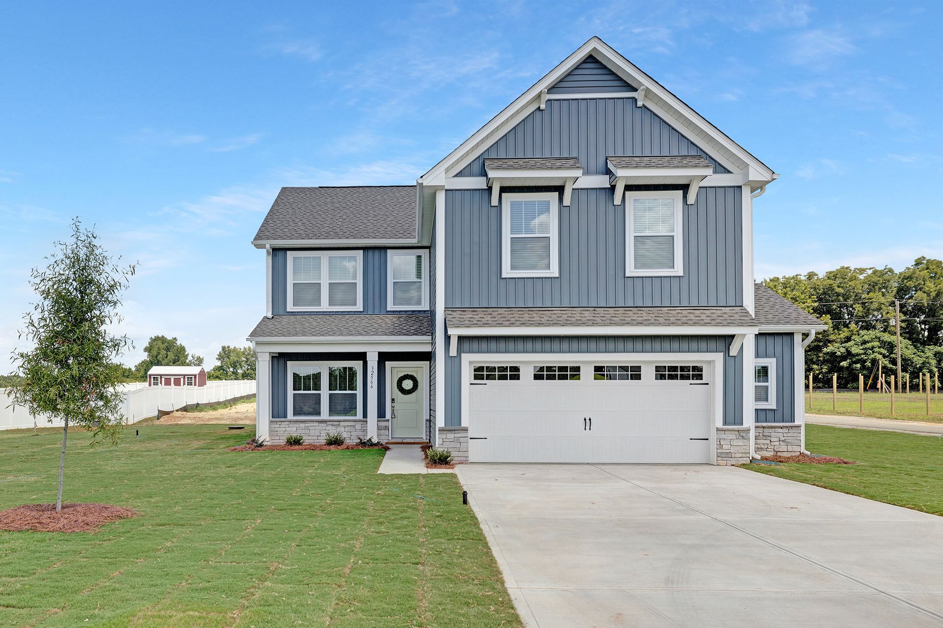 A large blue house with a white garage door is for sale.