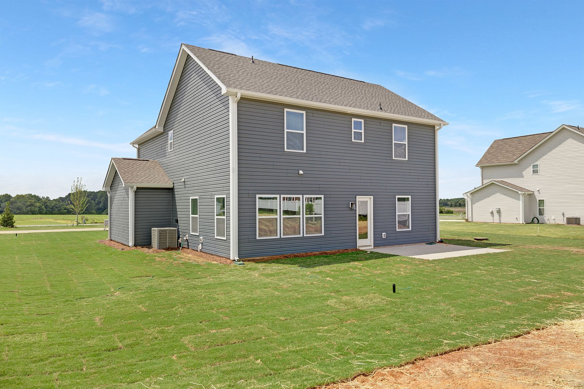 A large house with a lot of windows is sitting on top of a lush green field.