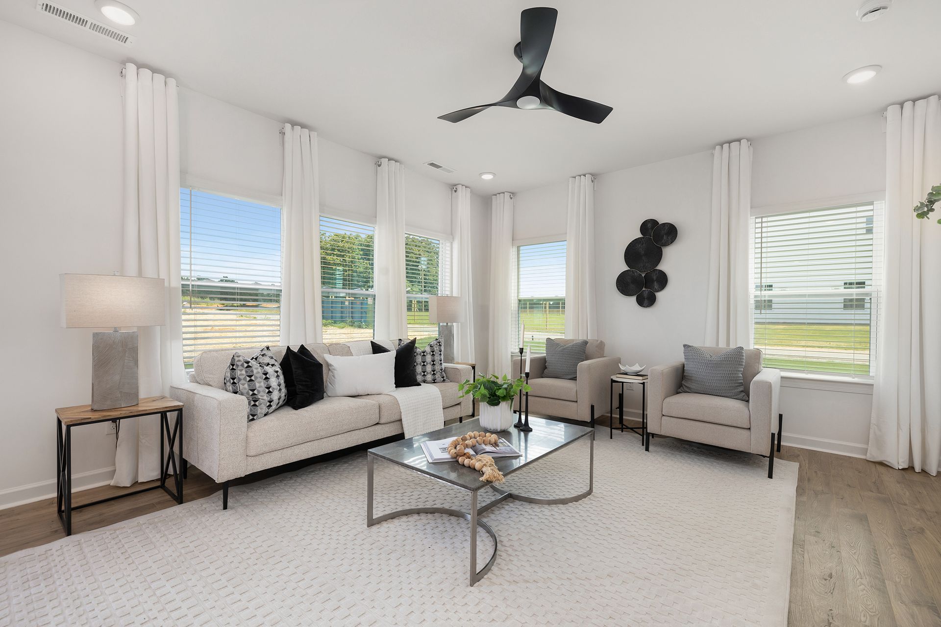 A living room with a couch , chairs , coffee table and ceiling fan.