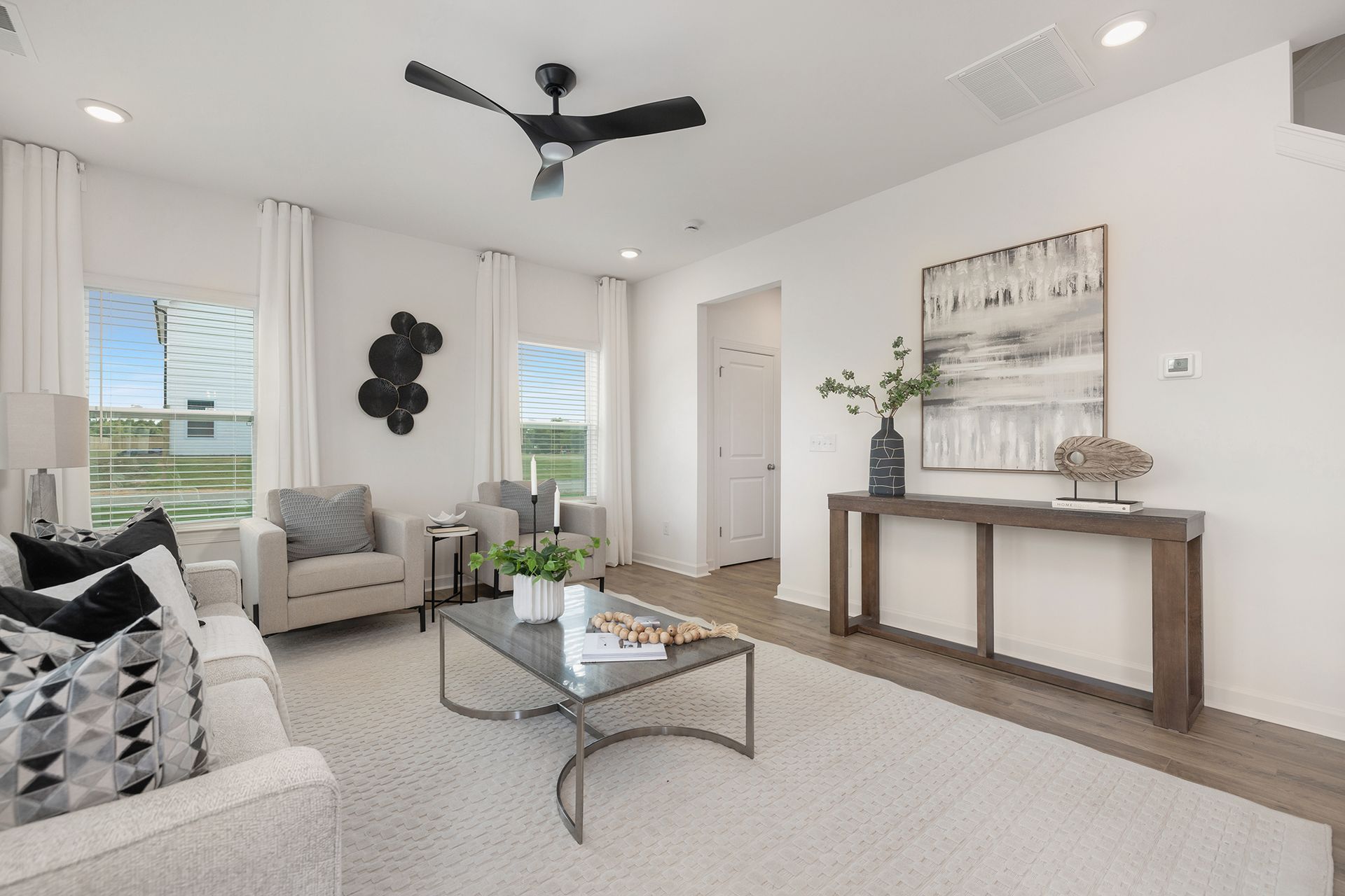 A living room with a ceiling fan and a couch and chairs