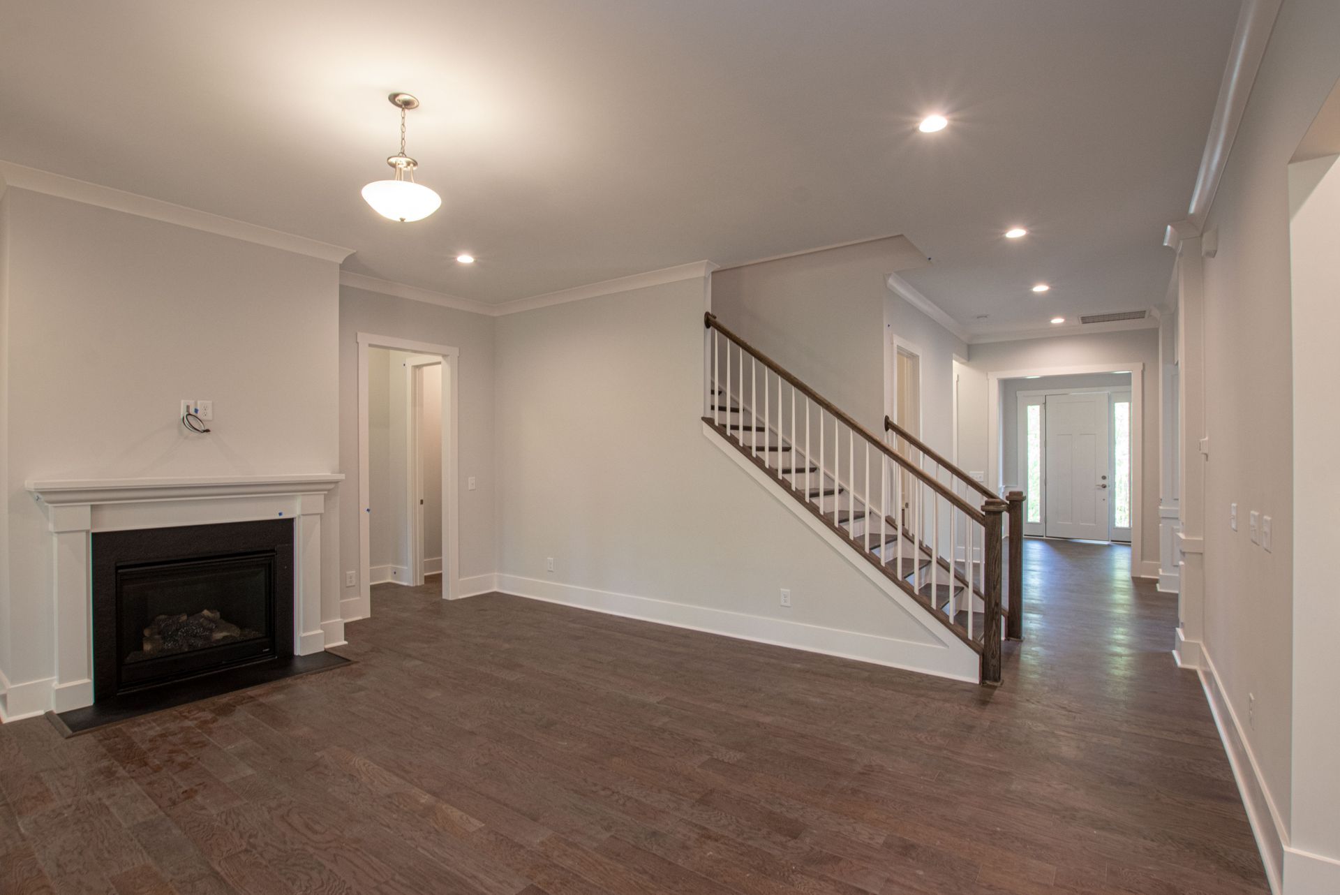 An empty living room with a fireplace and stairs.
