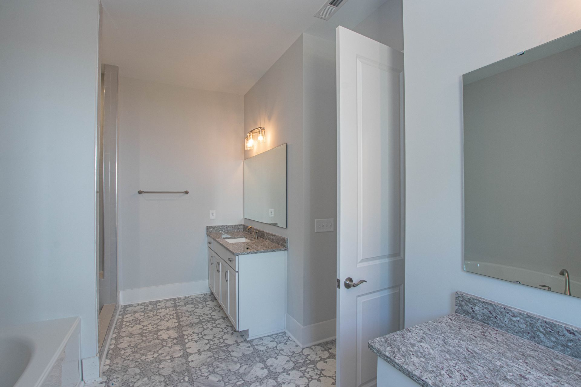 A bathroom with two sinks , a tub , and a mirror.