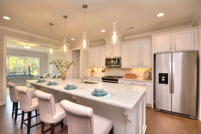 A kitchen with white cabinets , stainless steel appliances and a large island.