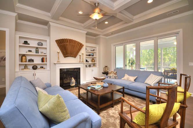 A living room with a blue couch , chairs , coffee table and fireplace.