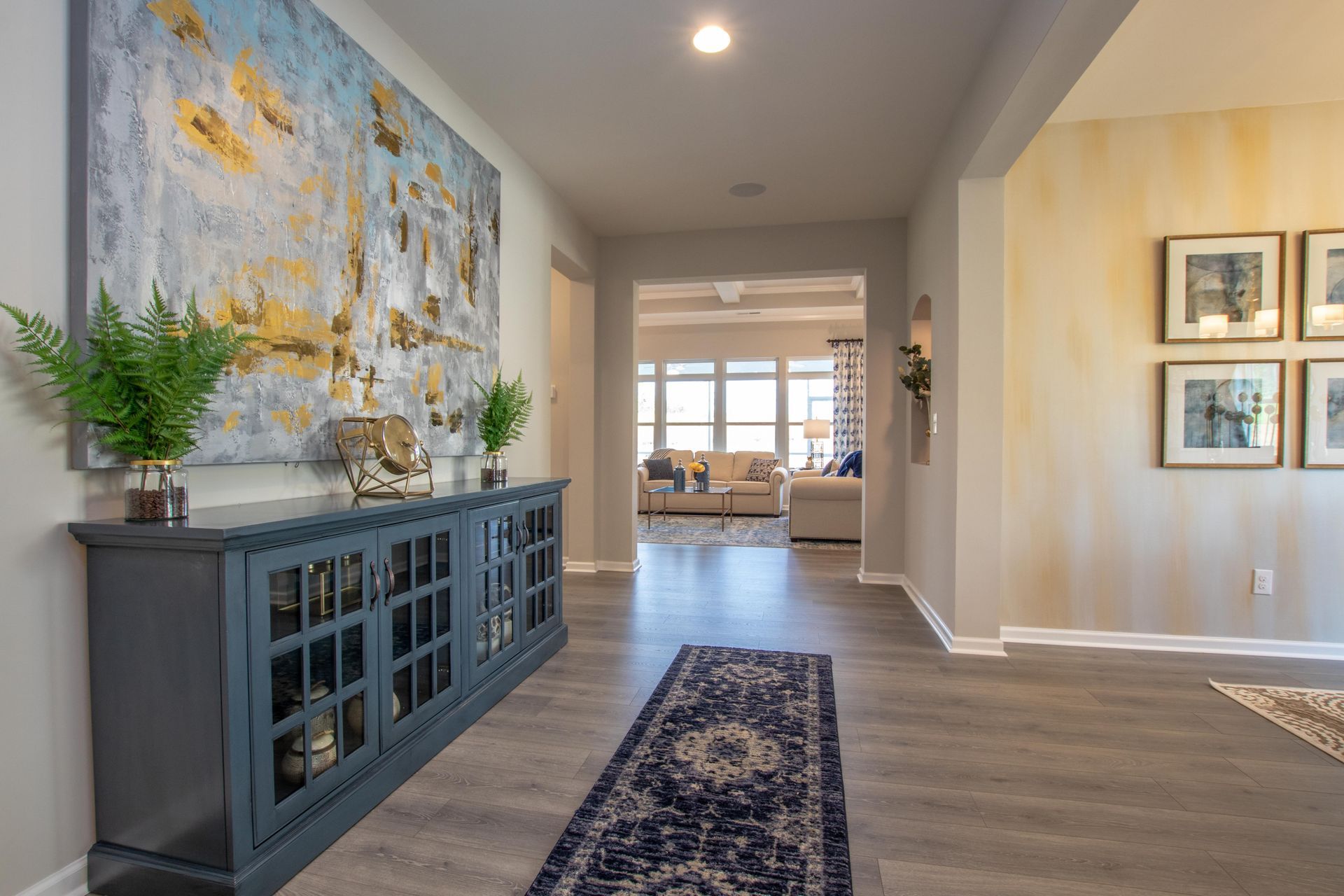 A hallway in a house with a painting on the wall and a rug.