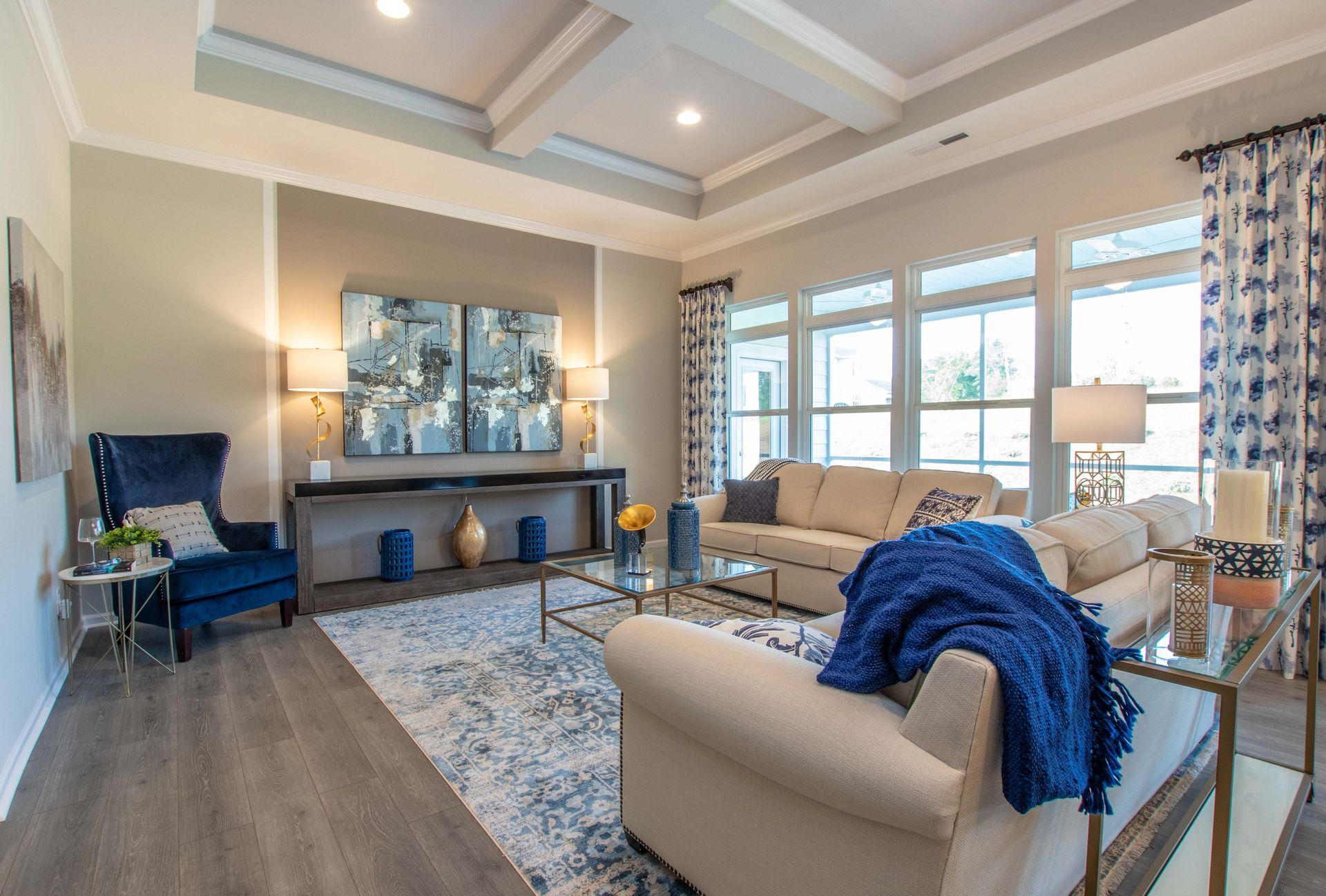 A living room with a couch , chair , table and lots of windows.
