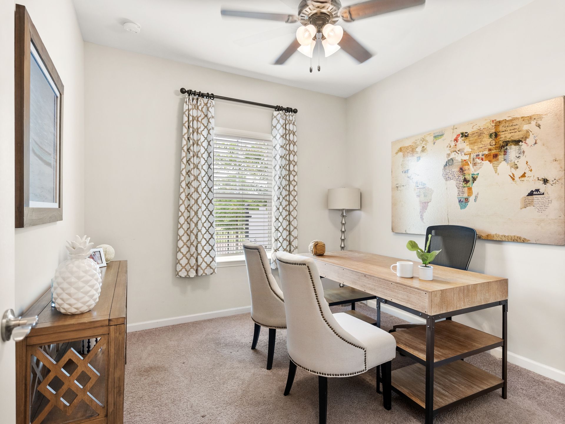 A home office with a desk , chairs and a ceiling fan.