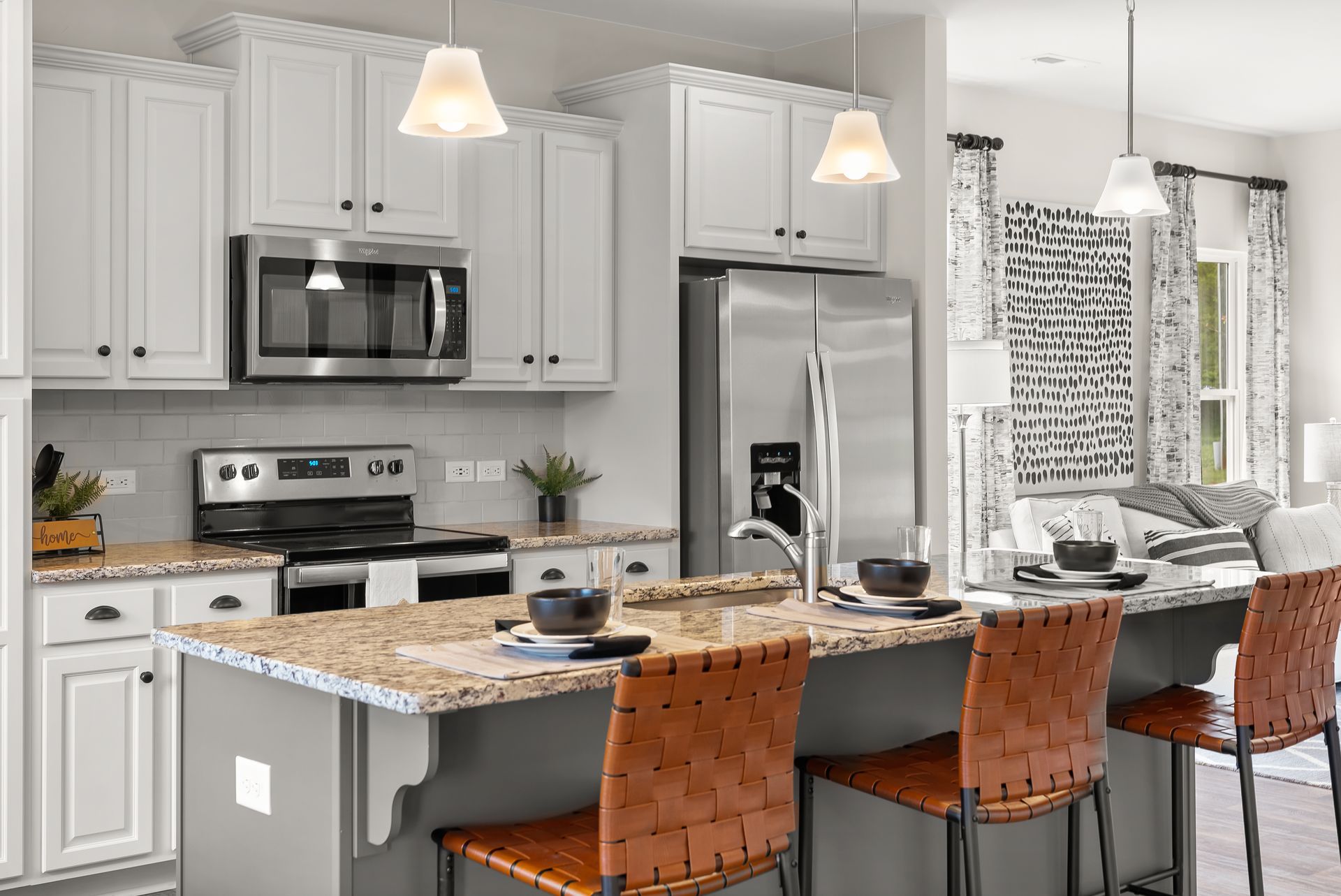 A kitchen with white cabinets , stainless steel appliances , granite counter tops and a large island.