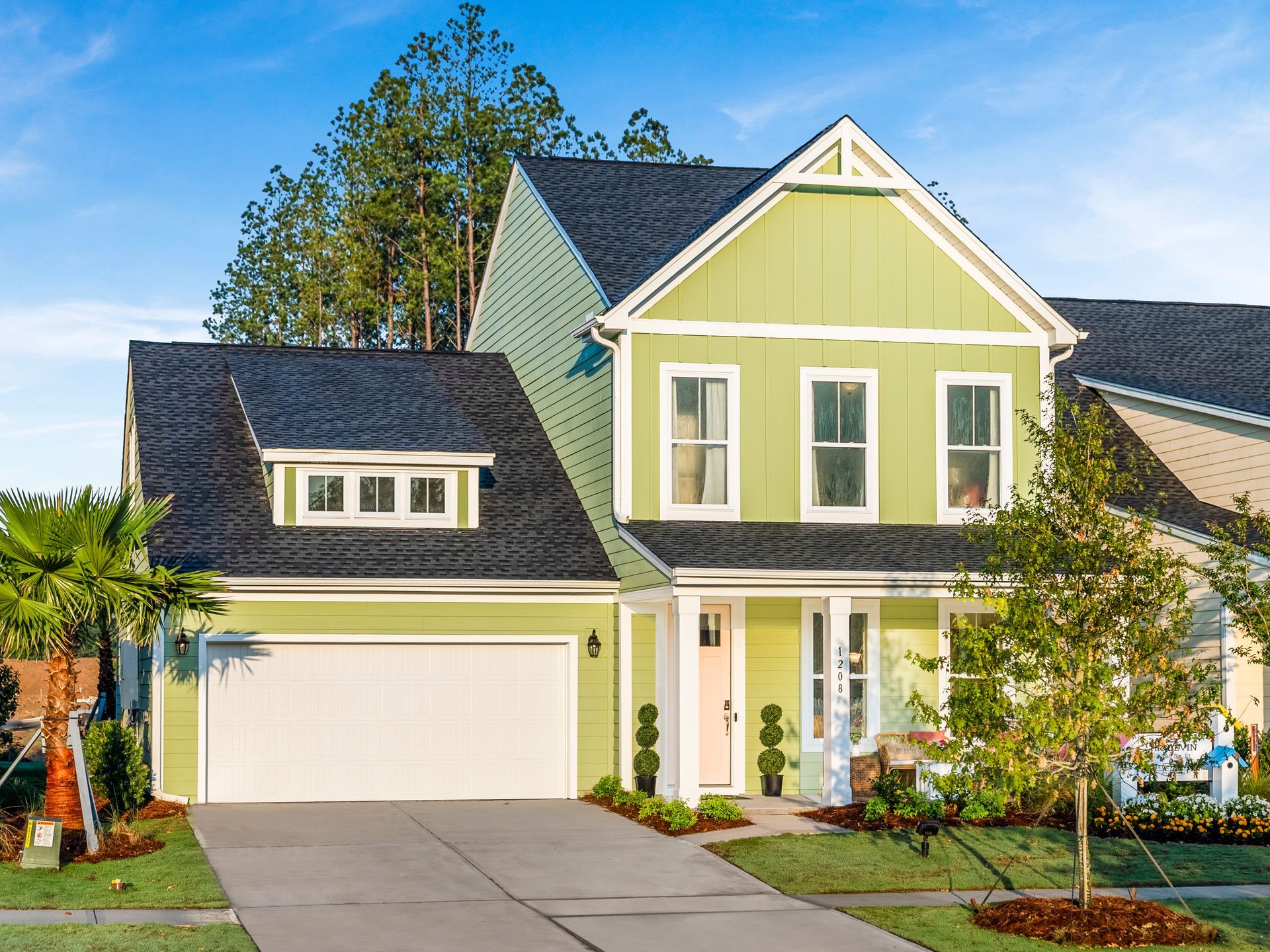 A green and white house with a black roof and a white garage door.