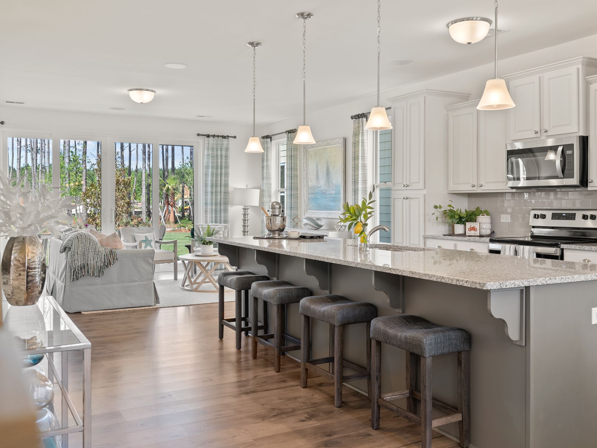 A kitchen with a long island and stools in a model home.