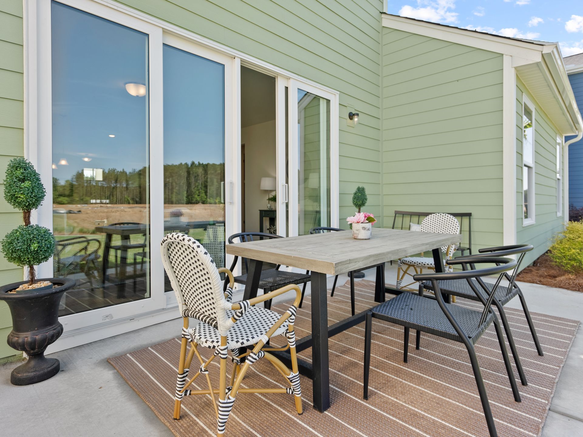 A patio with a table and chairs in front of a green house.