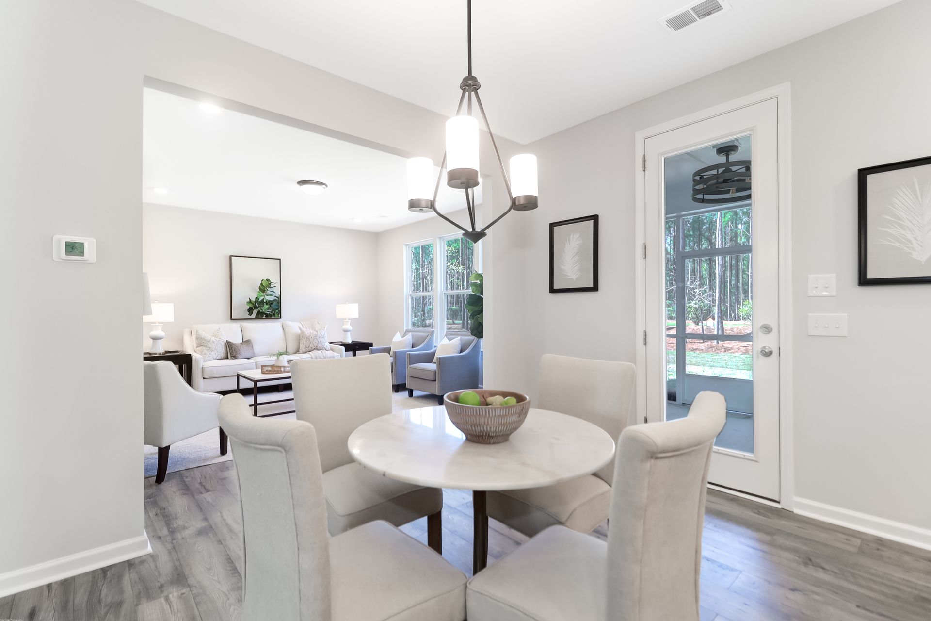 A dining room with a round table and chairs and a chandelier.