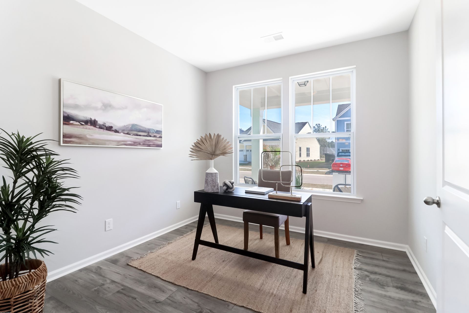 A home office with a desk and chairs and a large window.