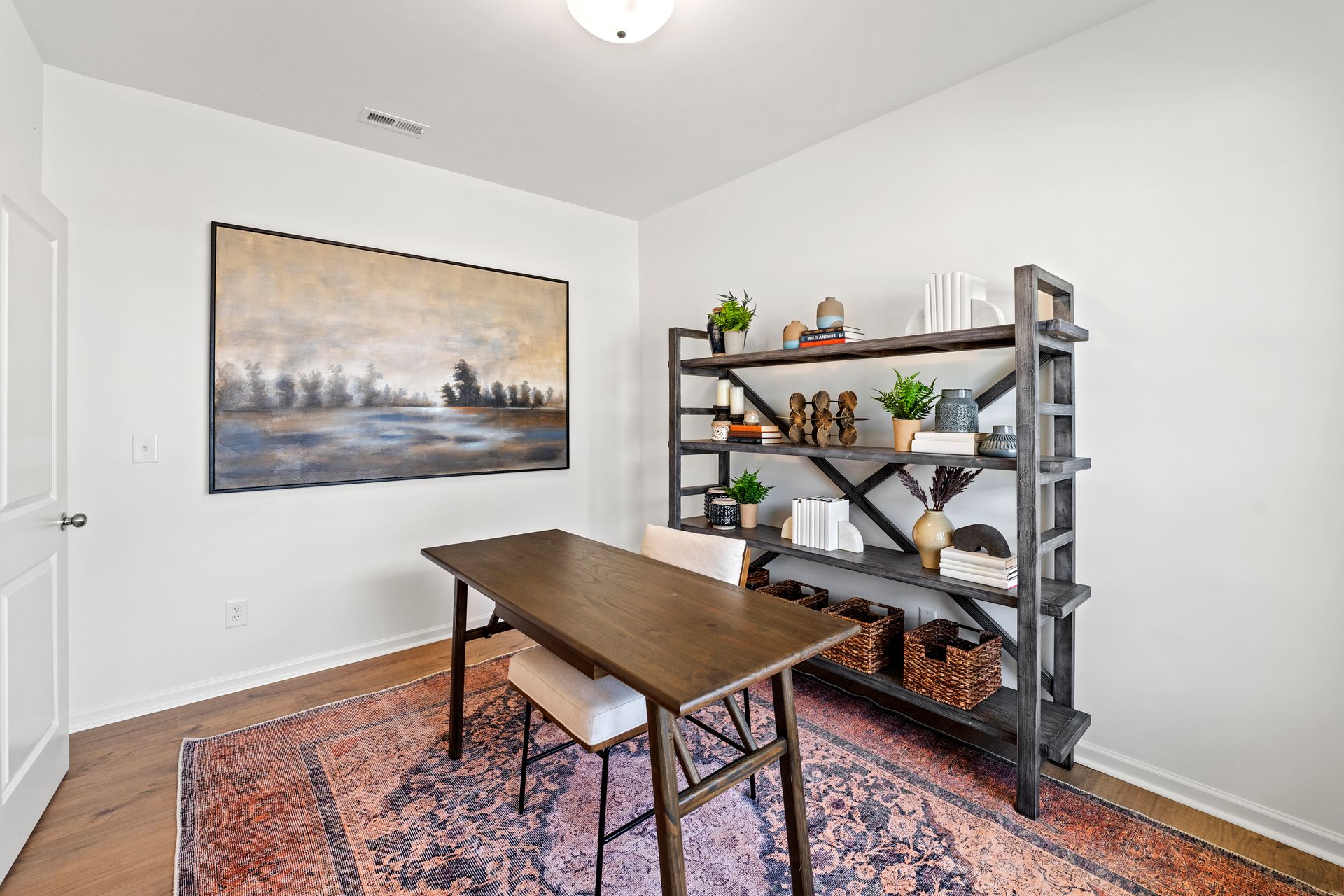 There is a painting on the wall above the desk in the room.