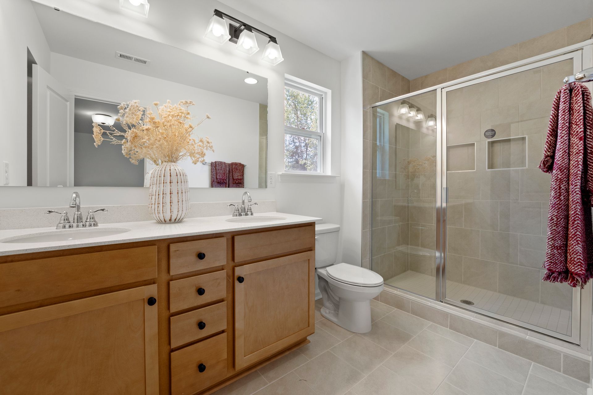 A bathroom with two sinks , a toilet , and a walk in shower.