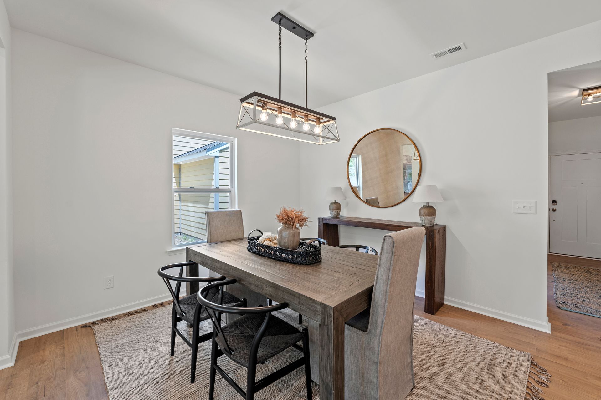 A dining room with a table and chairs and a mirror.
