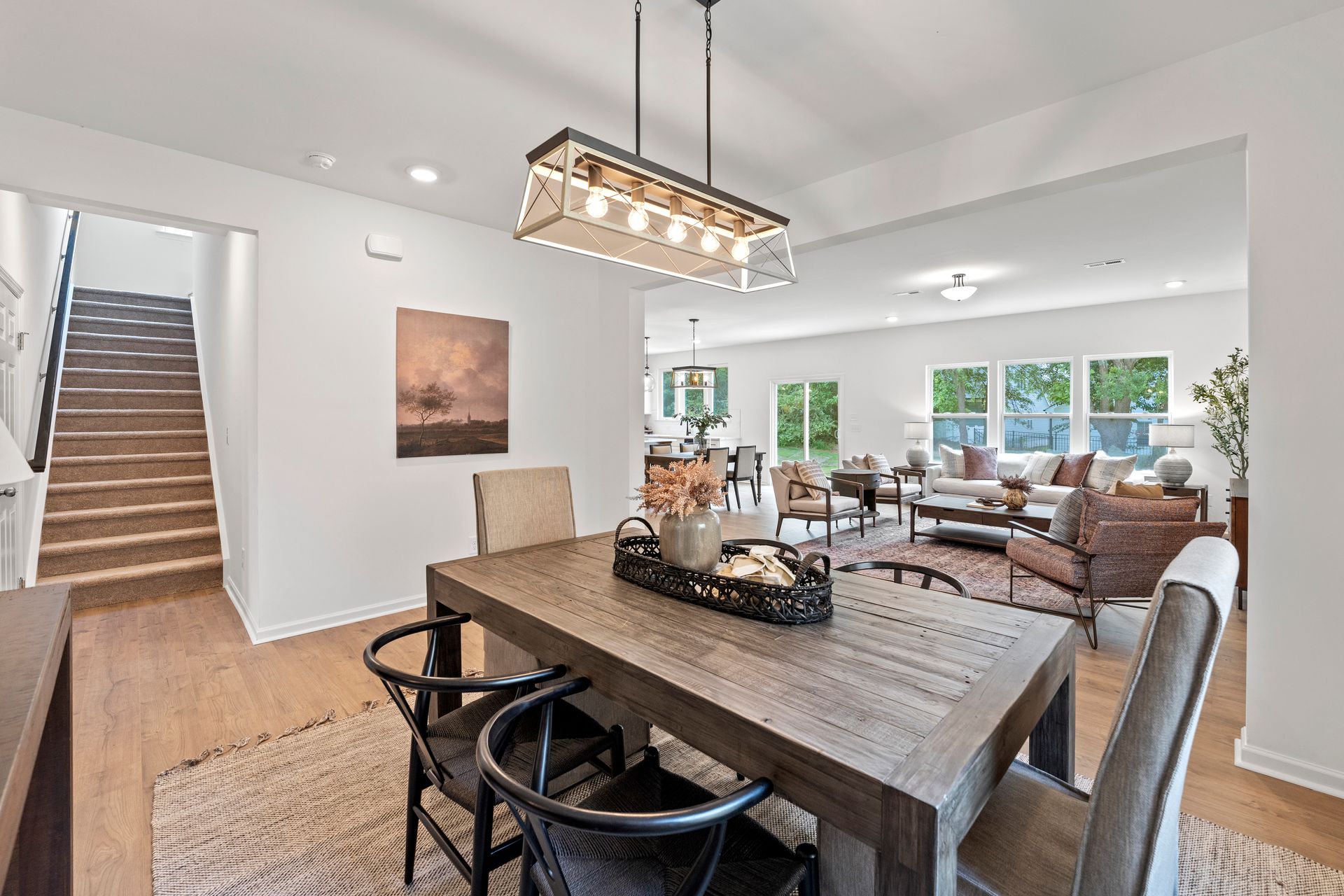 A dining room table with chairs and a chandelier in a house.