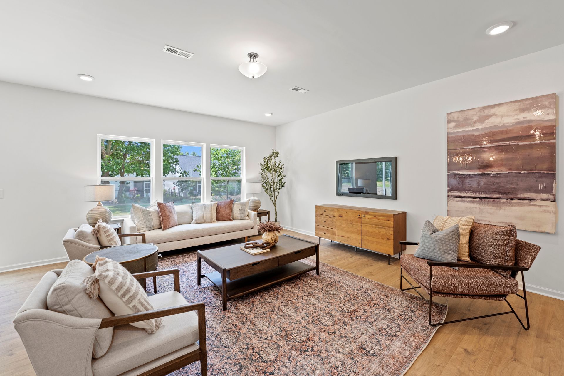 A living room with a couch , chairs , coffee table and television.