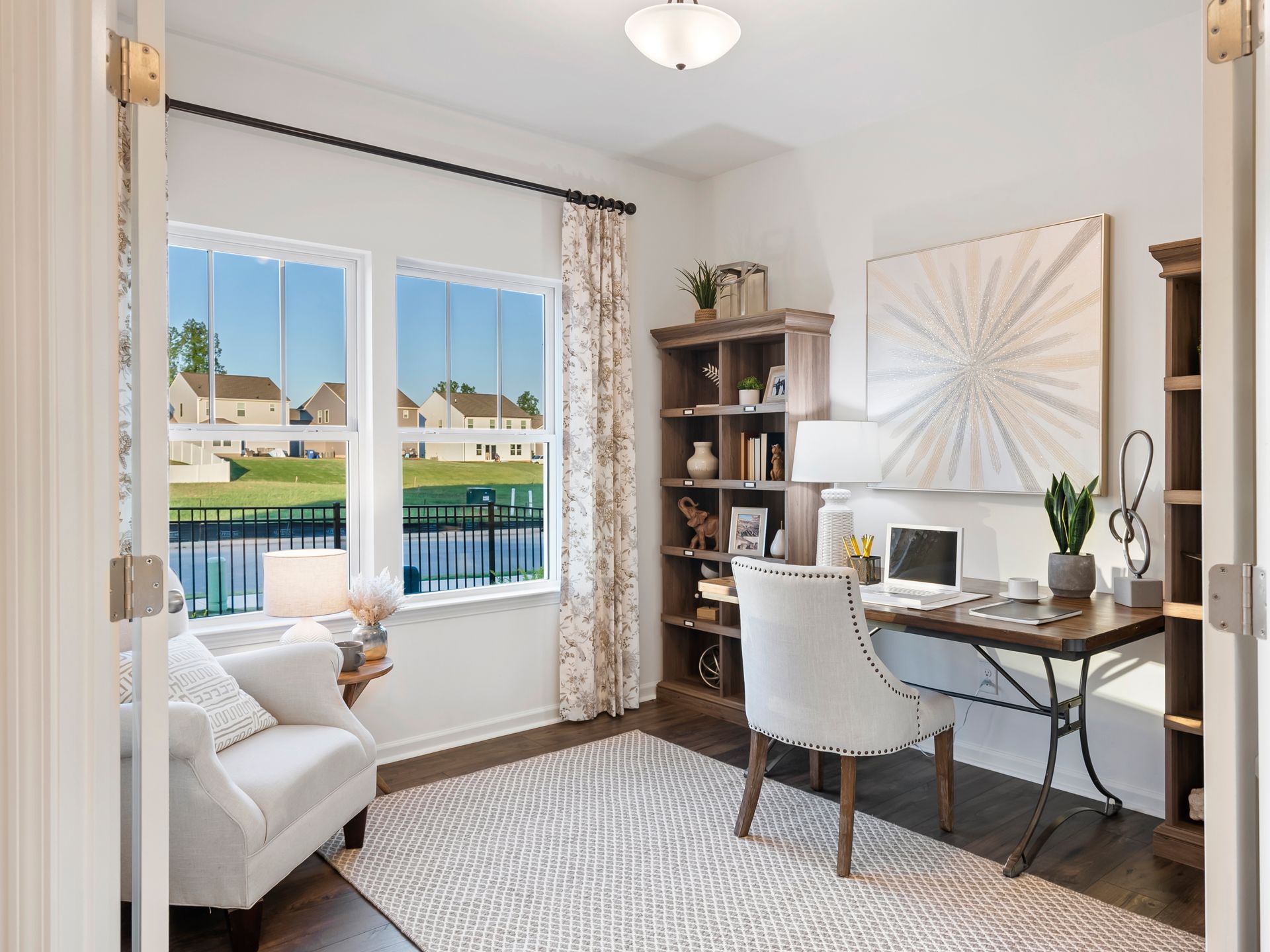 A home office with a desk , chair , bookshelf and window.