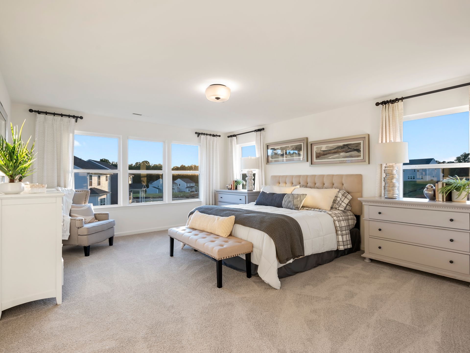 A bedroom with a large bed , dresser , chair and window.
