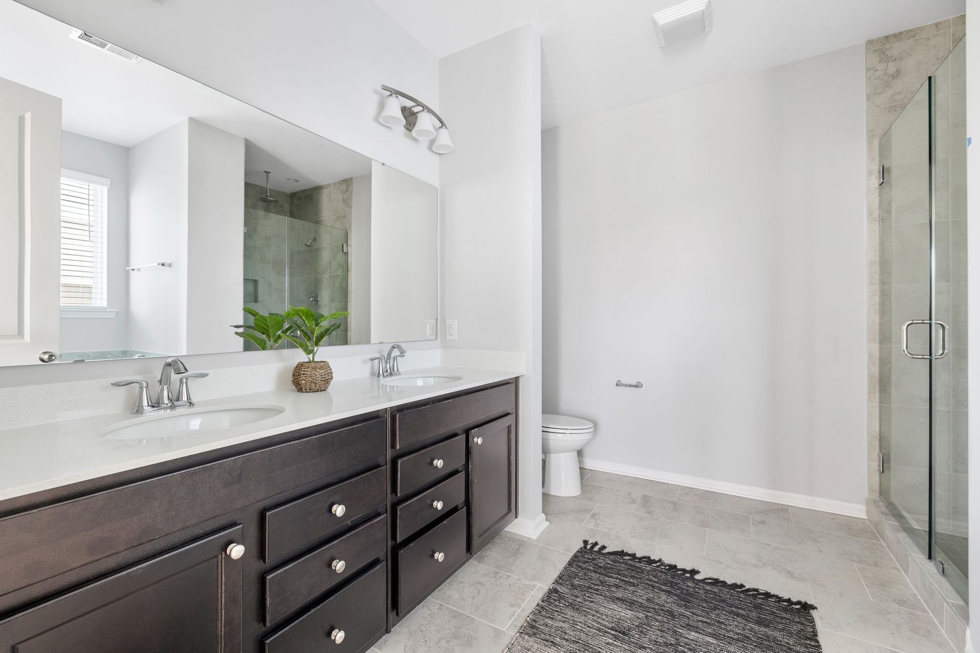 A bathroom with two sinks , a toilet , and a walk in shower.