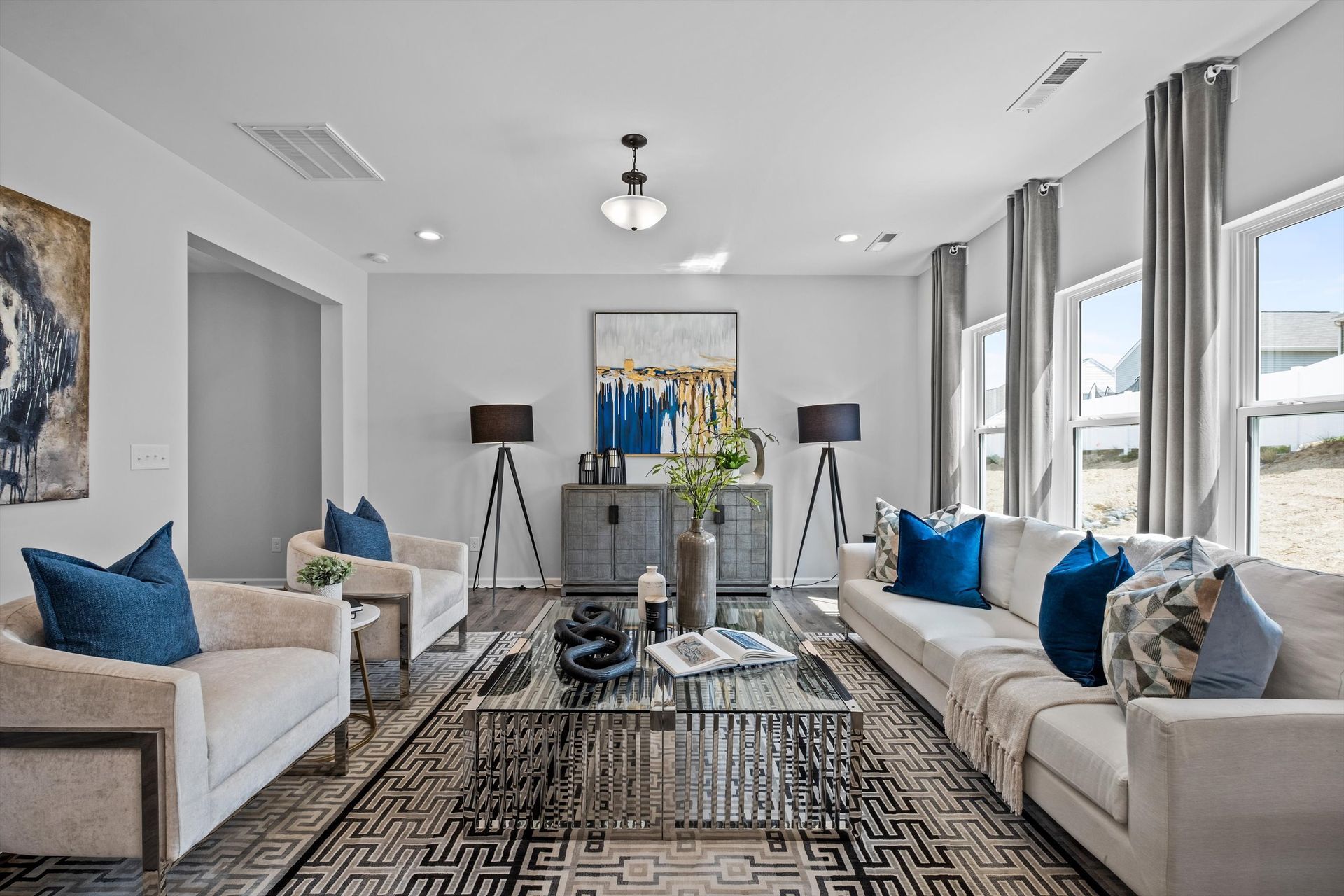 A living room with two couches , two chairs , a coffee table and a painting on the wall.