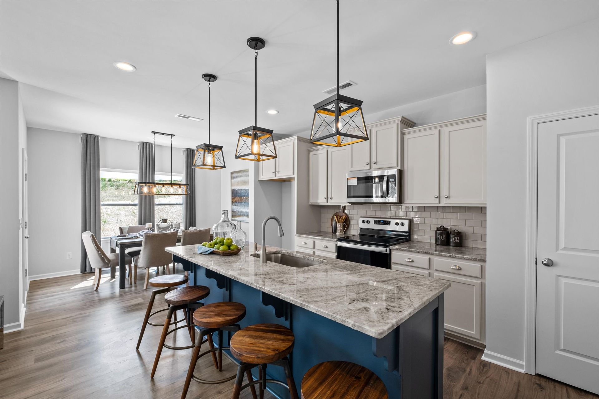 A kitchen in a model home with a large island and stools.