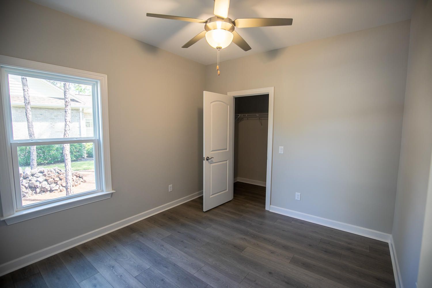 An empty bedroom with a ceiling fan and a window.